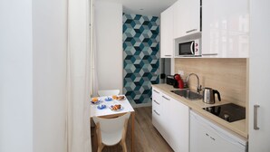 A compact kitchen with white cabinets, a microwave, a kettle, and a sink. - Studio original et reposant - Paris 10 - 2P (Paris)