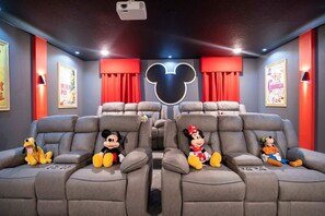 A home theater with plush seating, a large Mickey Mouse head decoration, and posters on the walls.