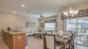A spacious living area with a dining table, chairs, a sofa, and a kitchen island. - Prime Locale - Vacation Paradise (Kissimmee)