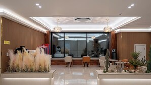 A modern reception area with a glass wall, wooden paneling, and a seating area with cacti and plants. - DK INCHEON AIRPORT HOTEL (Incheon)