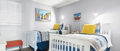 A bedroom with two single beds, a red bench, and a radiator.