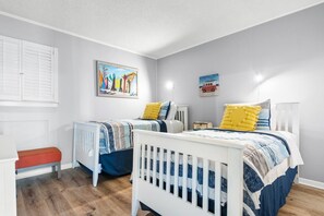 A bedroom with two single beds, a red bench, and a radiator.