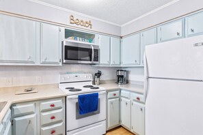 A kitchen with white cabinets, a microwave, stove, and a refrigerator.