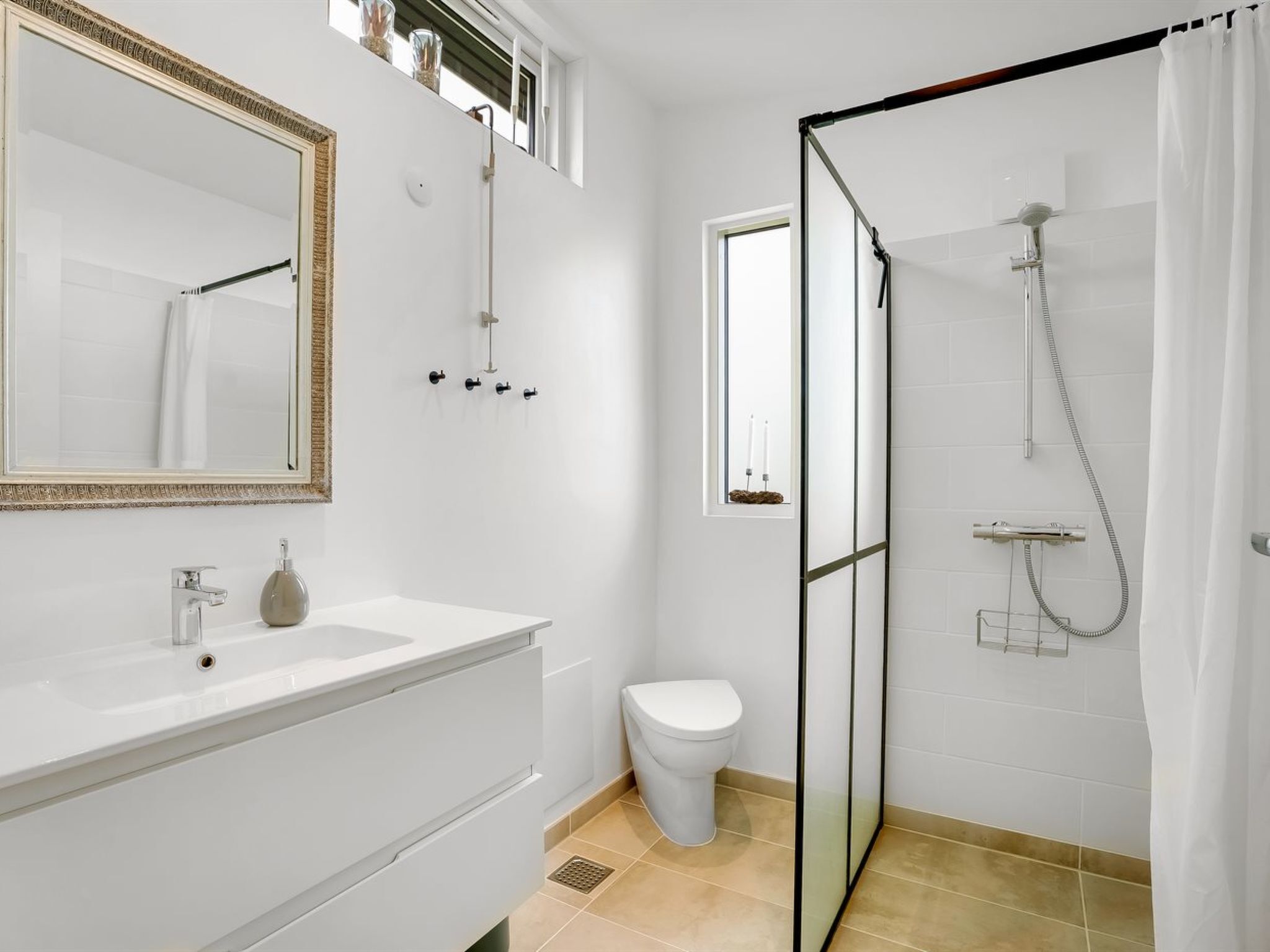 Ein modernes Badezimmer mit einem weißen Waschtisch, einer Toilette und einer Duschkabine.