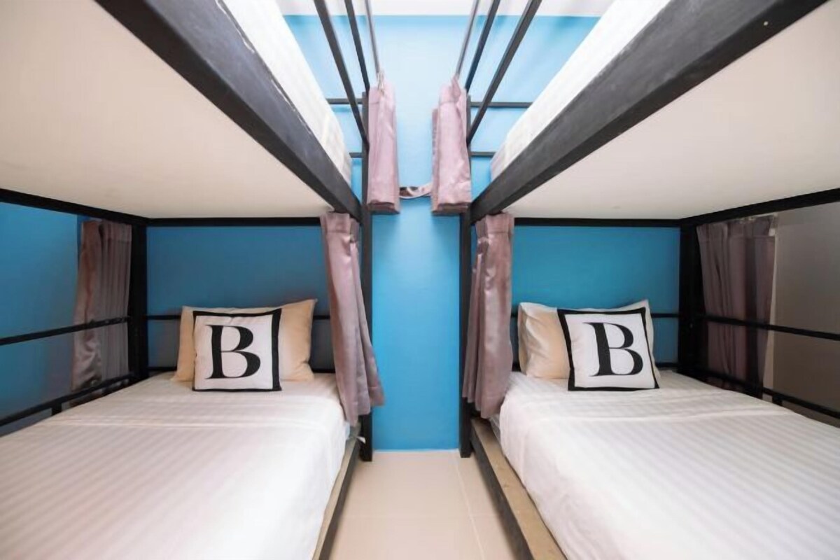Habitación con literas, dos camas, cada una con una almohada que lleva una gran letra 'B'.
