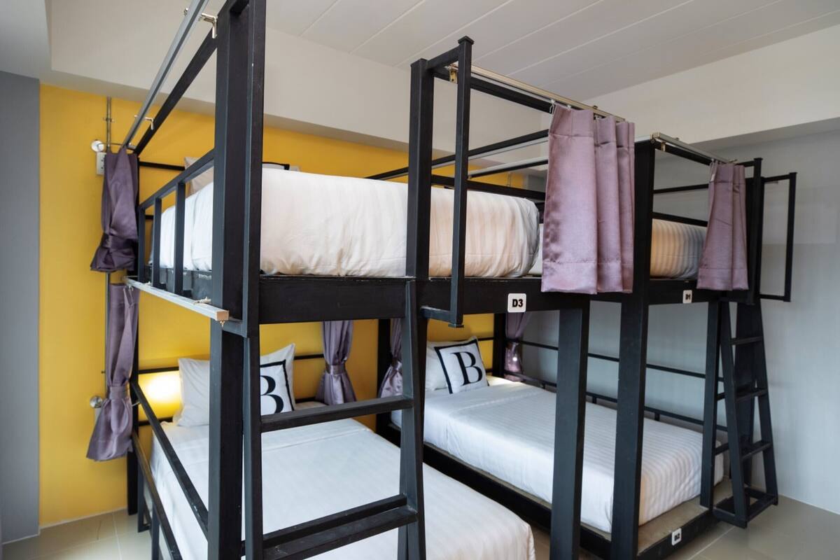 A bunk bed room with three beds, each with a pillow marked with a letter.