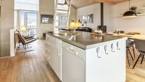 Eine moderne Küche mit einer zentralen Kochinsel, Holzboden und großen Fenstern.
