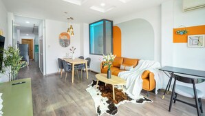 A modern living room with a sofa, a dining table, and a coffee table. There is a large window with a view of the outside. - SAZI Church View Home - Free Nails/HairWash (Ho Chi Minh City)