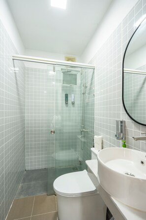 A modern bathroom with a glass-enclosed shower, a white toilet, and a large sink with a mirror. - SAZI Church View Home - Free Nails/HairWash (Ho Chi Minh City)