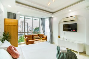 A modern hotel room with a large bed, a leather sofa, a TV, and a view of the city. - SAZI Church View Home - Free Nails/HairWash (Ho Chi Minh City)