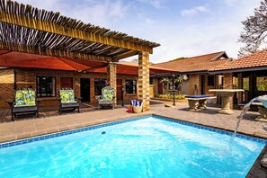 Une piscine avec des chaises longues et une pergola.