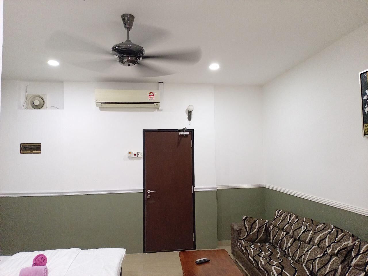 Une pièce comprenant un lit, un canapé, un ventilateur de plafond, un appareil de climatisation et une porte.