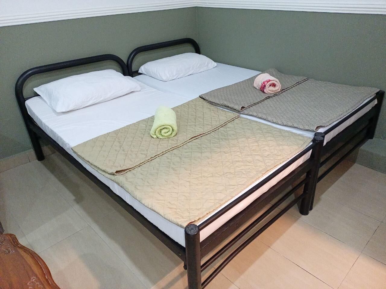 Una cama doble con colcha, almohadas y una toalla enrollada.