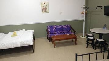 Una habitación con cama, sofá, una mesita y una silla.