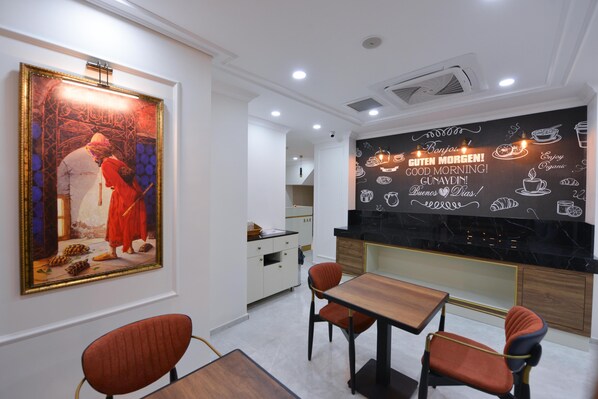 Un espace repas moderne agrémenté d’un grand tableau encadré, d’un comptoir en marbre noir et d’un mur orné d’illustrations et de textes sur le thème du petit-déjeuner.