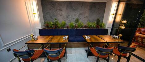 Un comedor moderno con una mesa larga, múltiples sillas y un sofá azul.