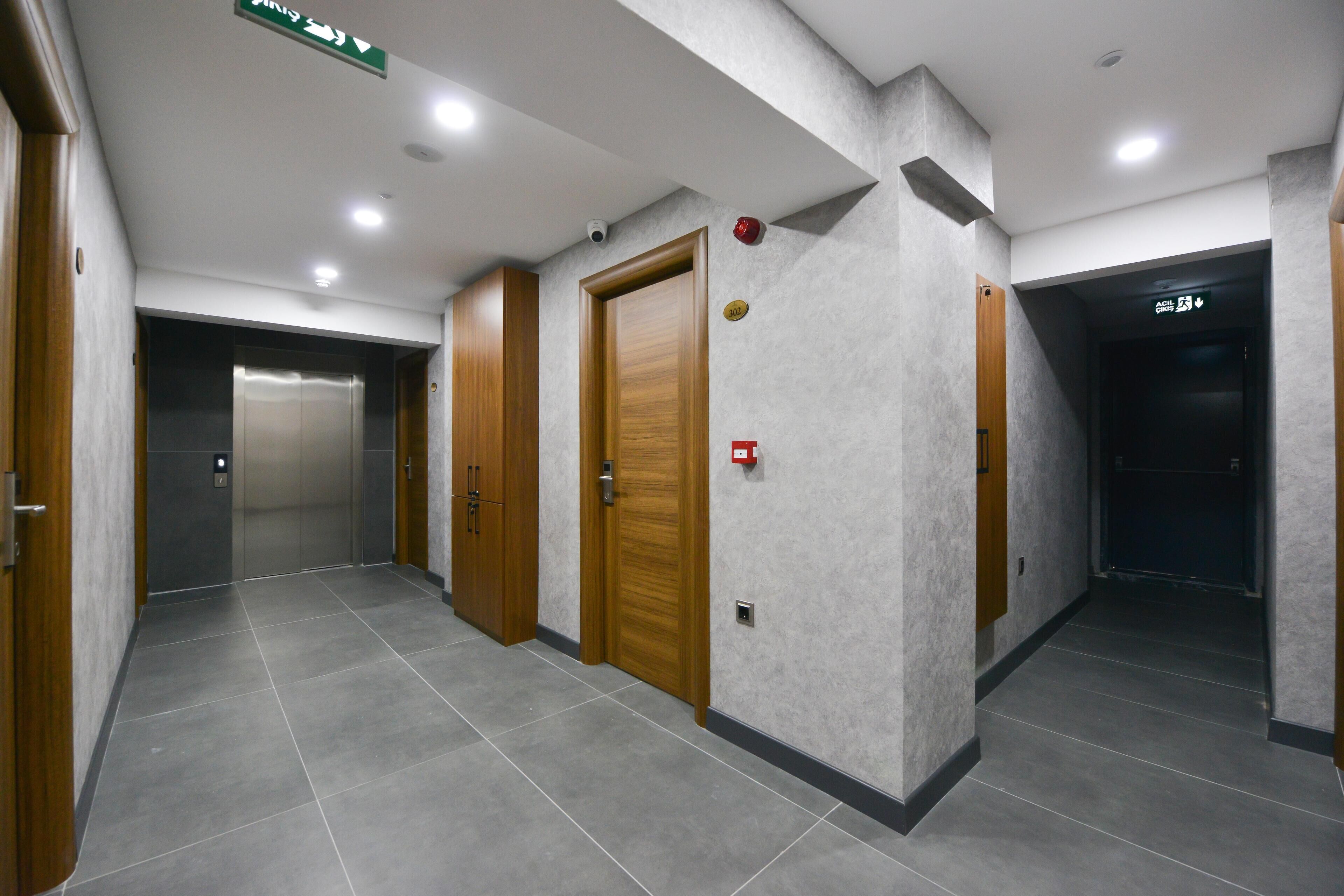 A hallway with wooden doors, a fire alarm, and an elevator.