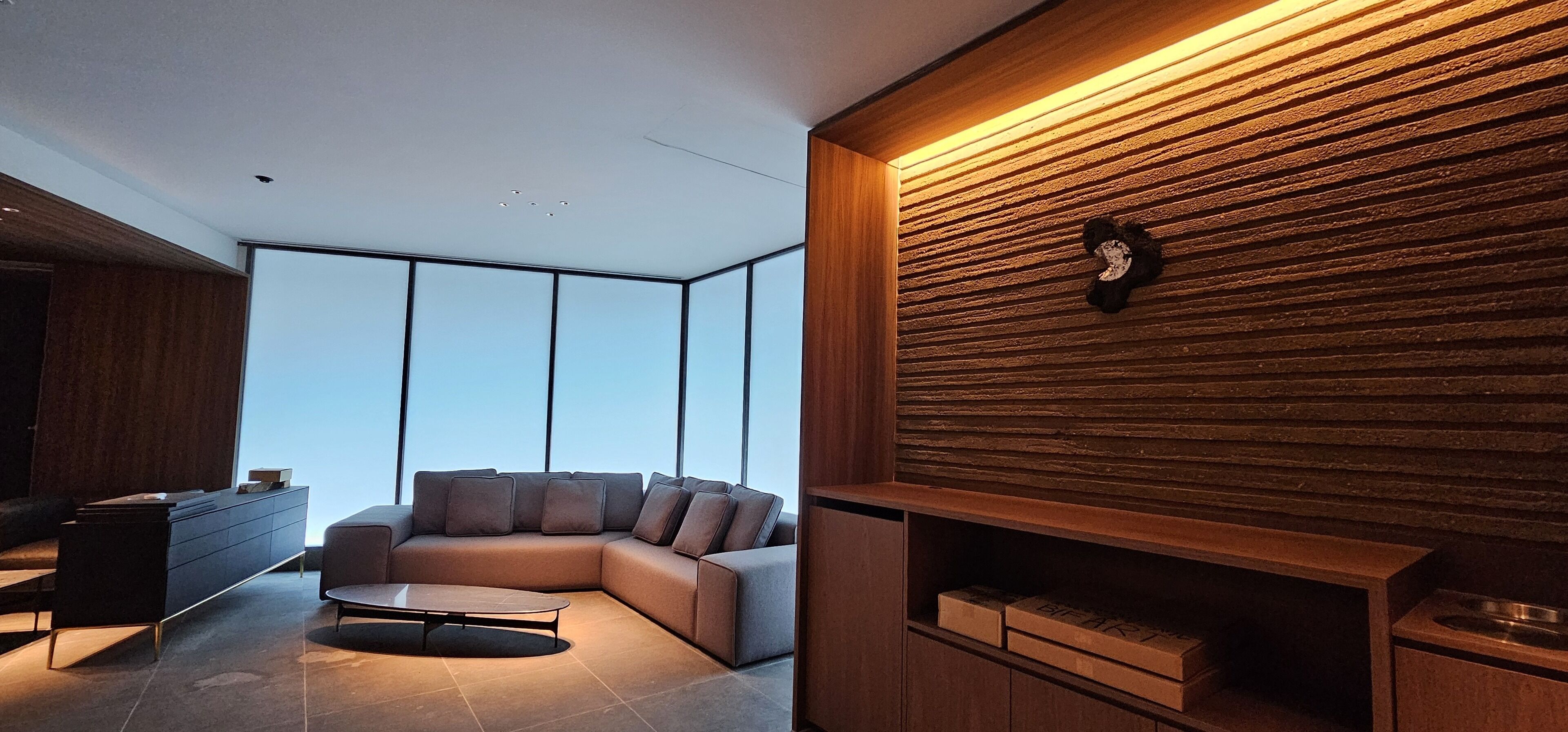 Uma sala de estar moderna com um sofá seccional, uma mesa de centro e uma parede de destaque em madeira.