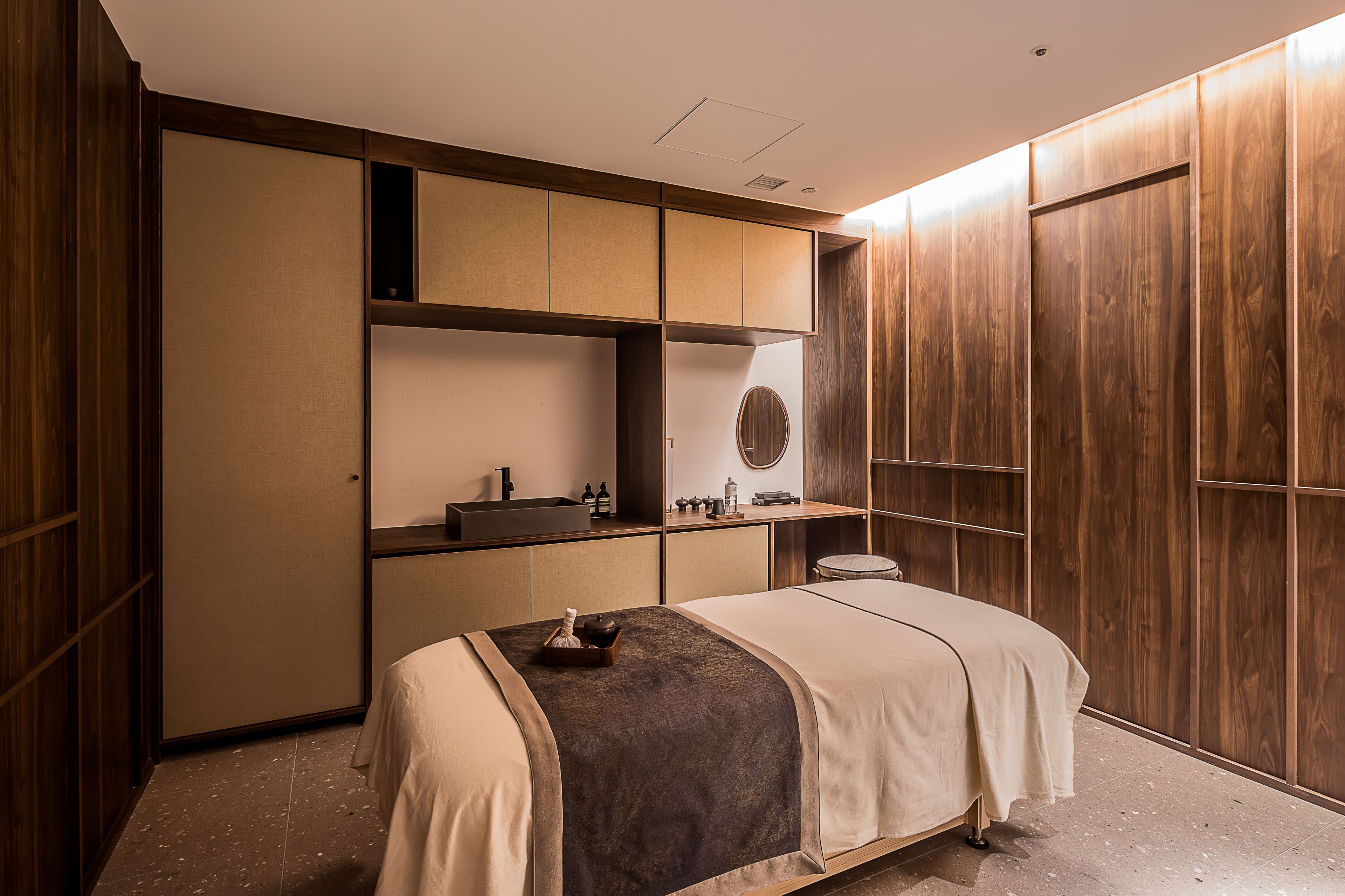 A modern bedroom with a bed, built-in wardrobe, and a small desk area.