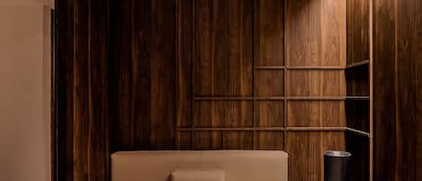 A modern room with a wooden panel wall, a sofa, a small round table, and two bowls.