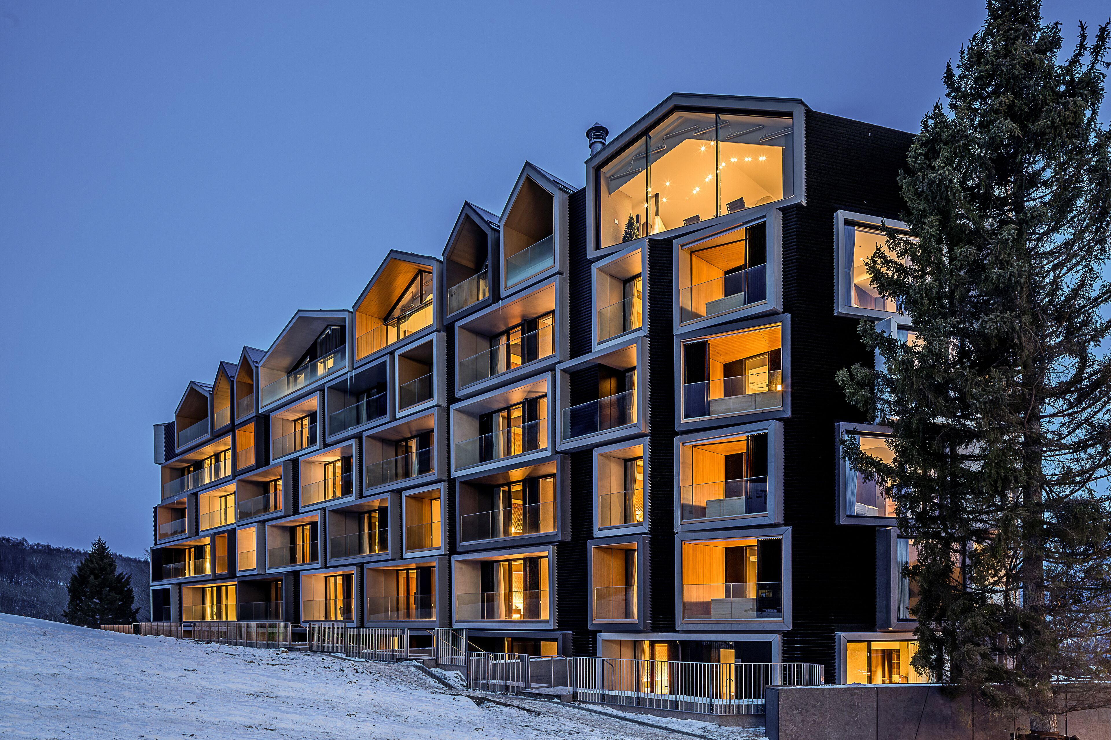 Un hôtel moderne à plusieurs étages, doté d’une façade symétrique, de grandes fenêtres et de balcons.