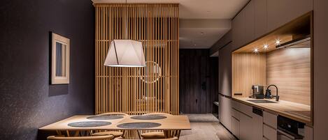 Una cocina moderna con una mesa de comedor de madera, sillas e iluminación colgante.