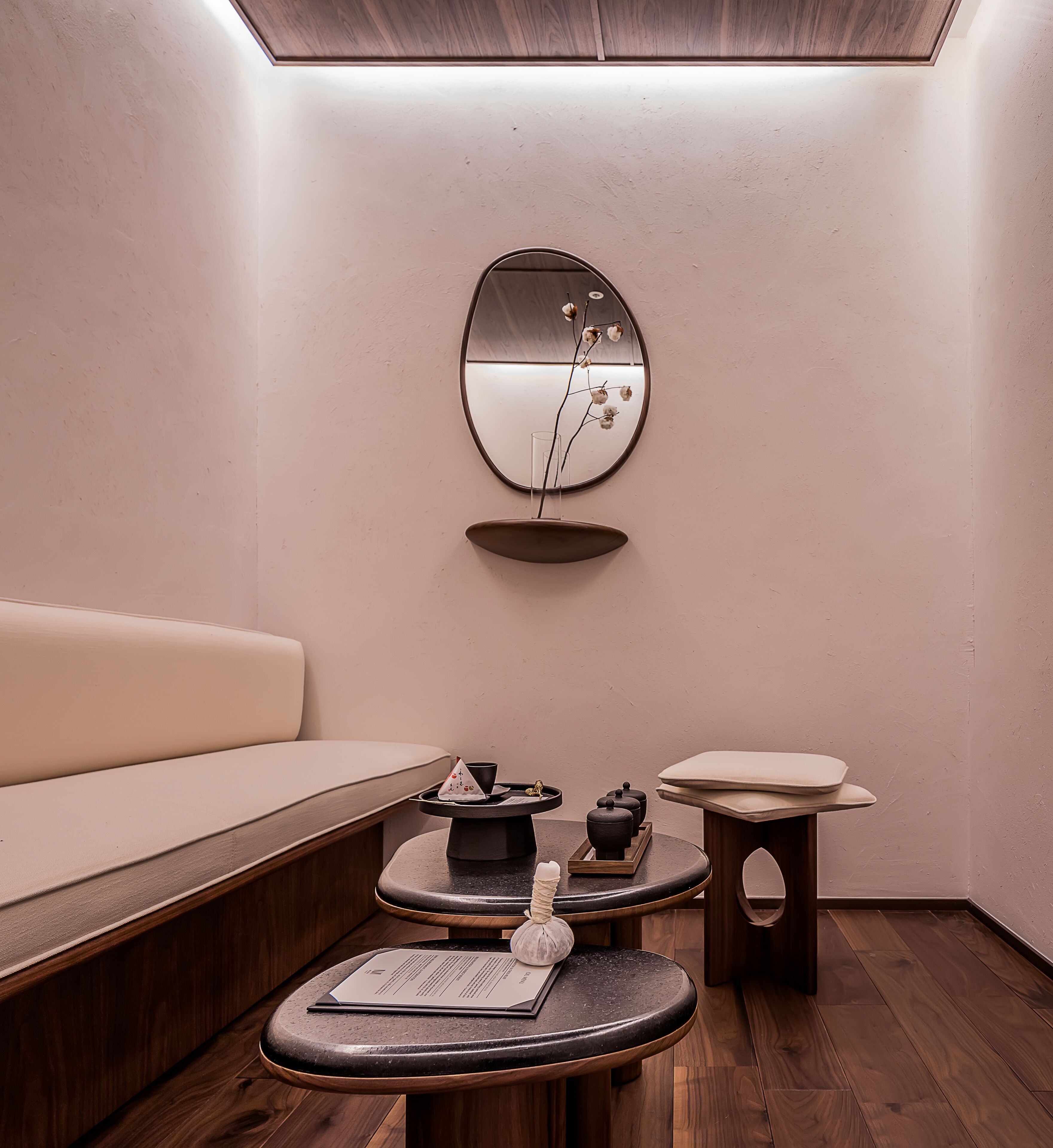 A modern, minimalist room with a sofa, a round mirror, and a small table with a bowl and a candle.