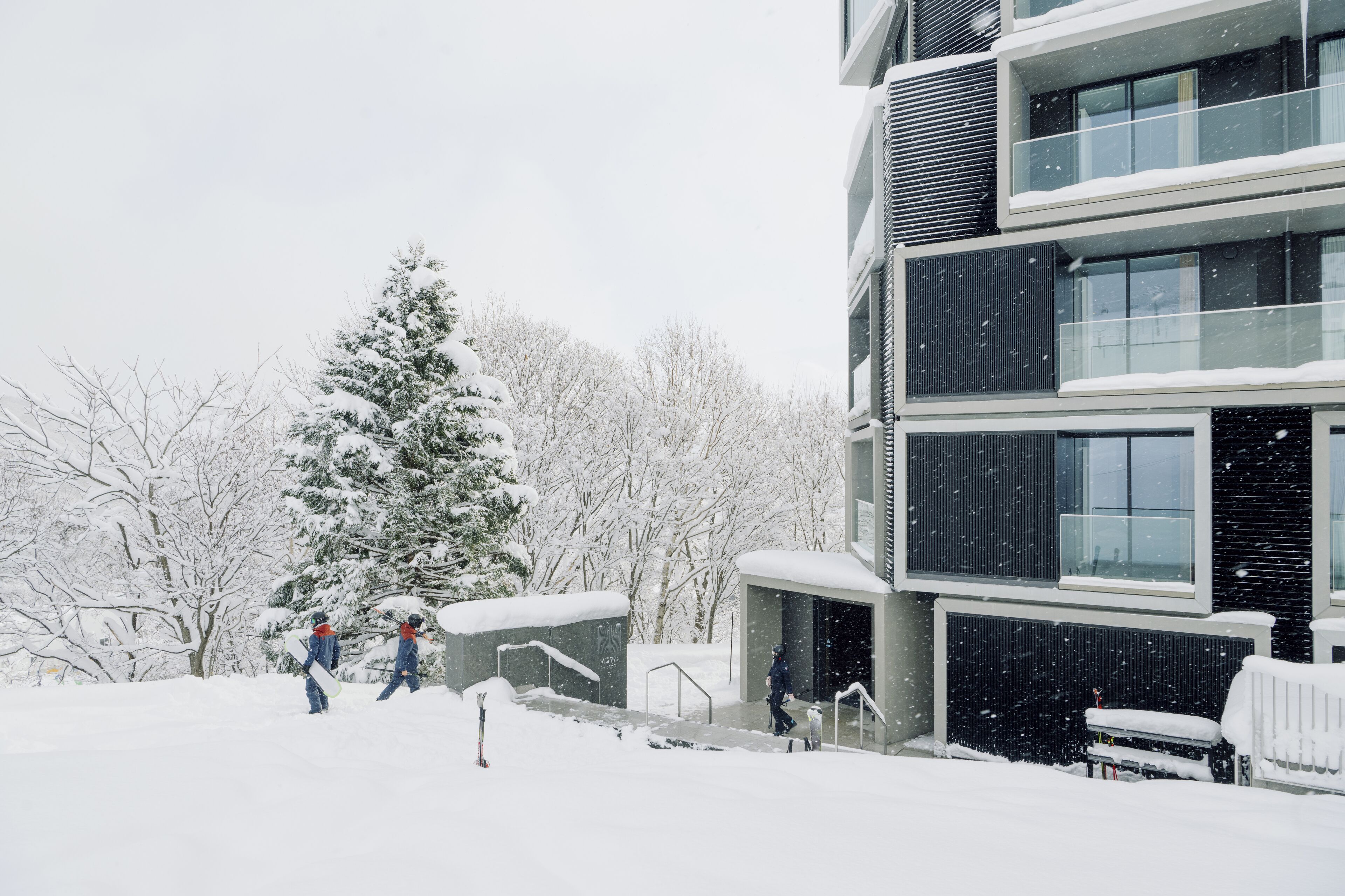 Un edificio moderno con varios balcones y un paisaje cubierto de nieve.