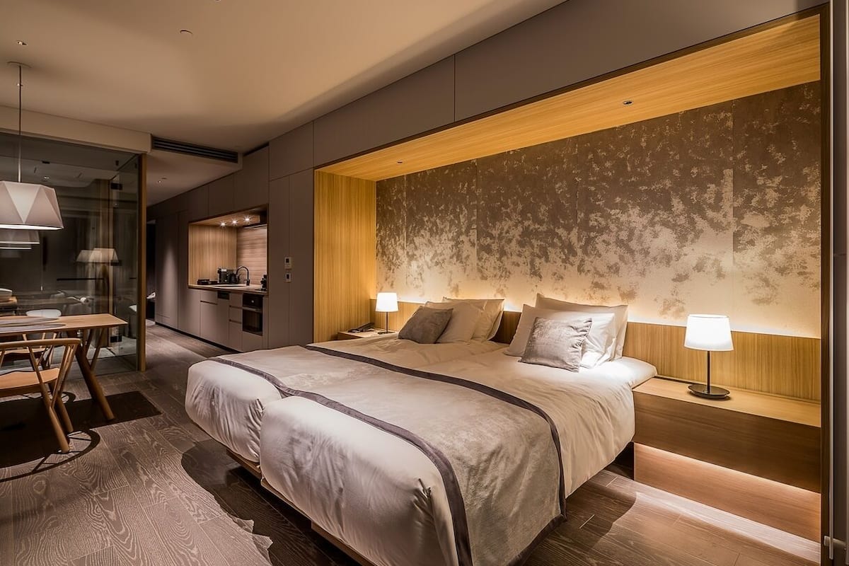 Una habitación de hotel moderna con una cama grande, mesitas de noche, un escritorio y un baño.