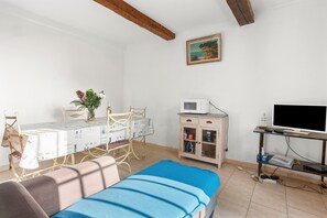 Ein Zimmer mit einem Bett, einem Tisch mit Stühlen, einem Schrank, einem Fernseher und einem Bild an der Wand.