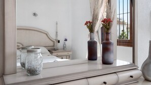 A bedroom with a bed, a nightstand, a mirror, and two vases on a dresser. - Holiday Home 'Torremuelle' with Sea Views, Pool, Terrace and Garden (Benalmadena)