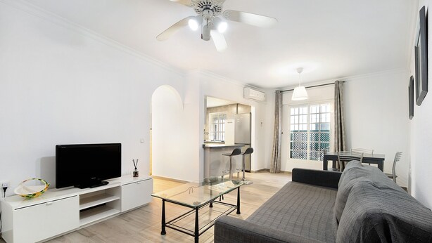 A modern living room with a flat-screen TV, glass coffee table, sofa, and dining area with chairs. - 'Ribera Del Marisco' Apartment with Air Conditioning (El Puerto de Santa María)