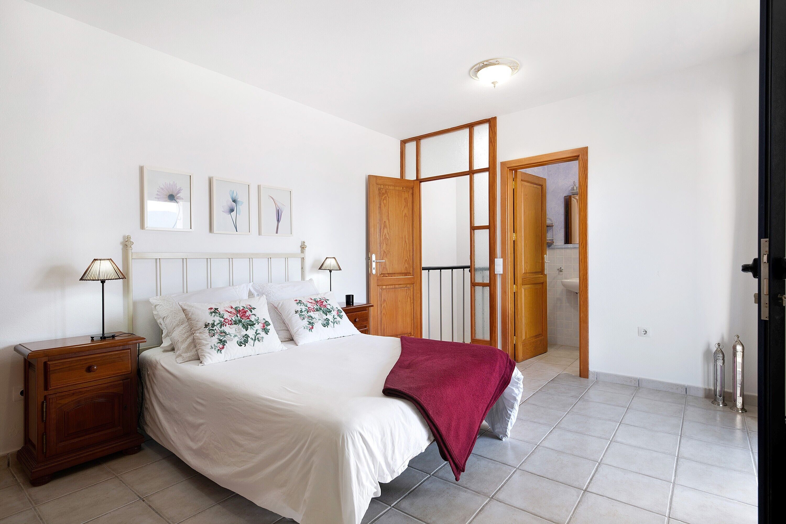 Un dormitorio con cama, mesita de noche y puerta de madera que da a otra habitación.