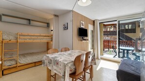 A compact room with a bunk bed, a dining table with chairs, a TV, and a balcony with a view. - Apartment 'Le Relais Du Devoluy' with Mountain View and Terrace (Le Dévoluy)