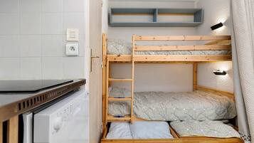 Een stapelbed met houten frame, een wasmachine en een plank boven het bed.