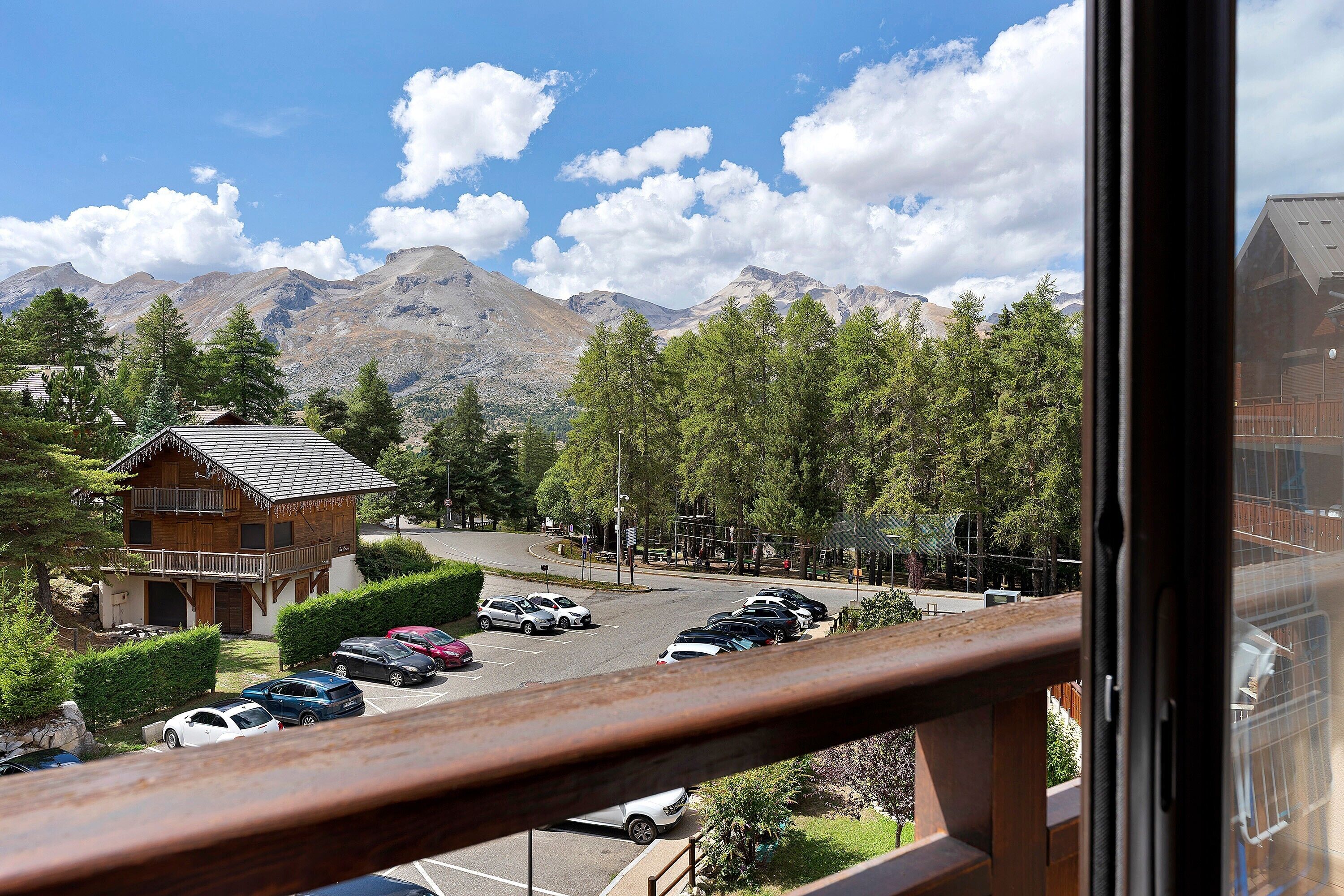 Une vue sur la montagne, avec un parking, un bâtiment en bois et un ciel dégagé.