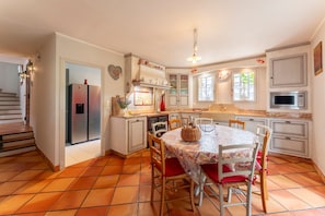 Une cuisine équipée d’une table à manger, de chaises, d’un réfrigérateur, de placards et d’une fenêtre.