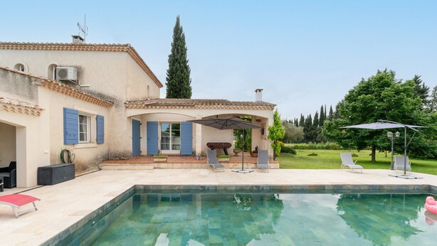 Una casa con piscina, mobiliario de exterior y jardín.