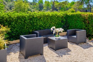 An outdoor seating area with dark wicker furniture and a vase of white flowers.
