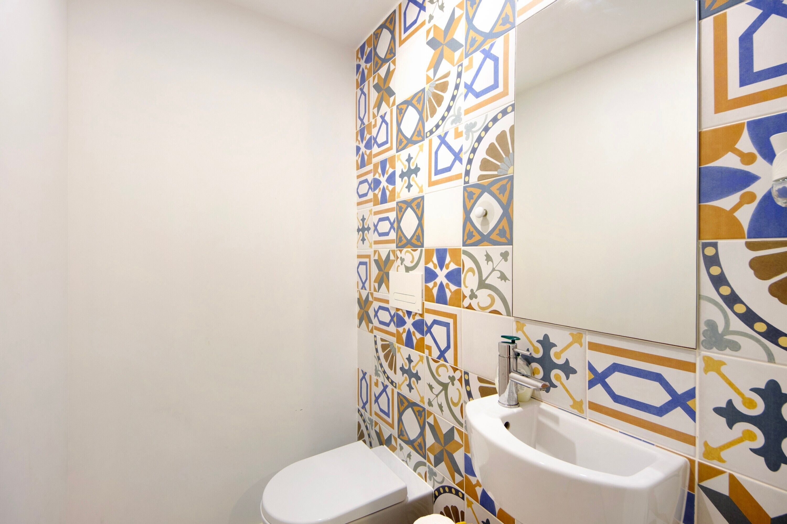 A bathroom with a toilet, sink, and tiled walls.