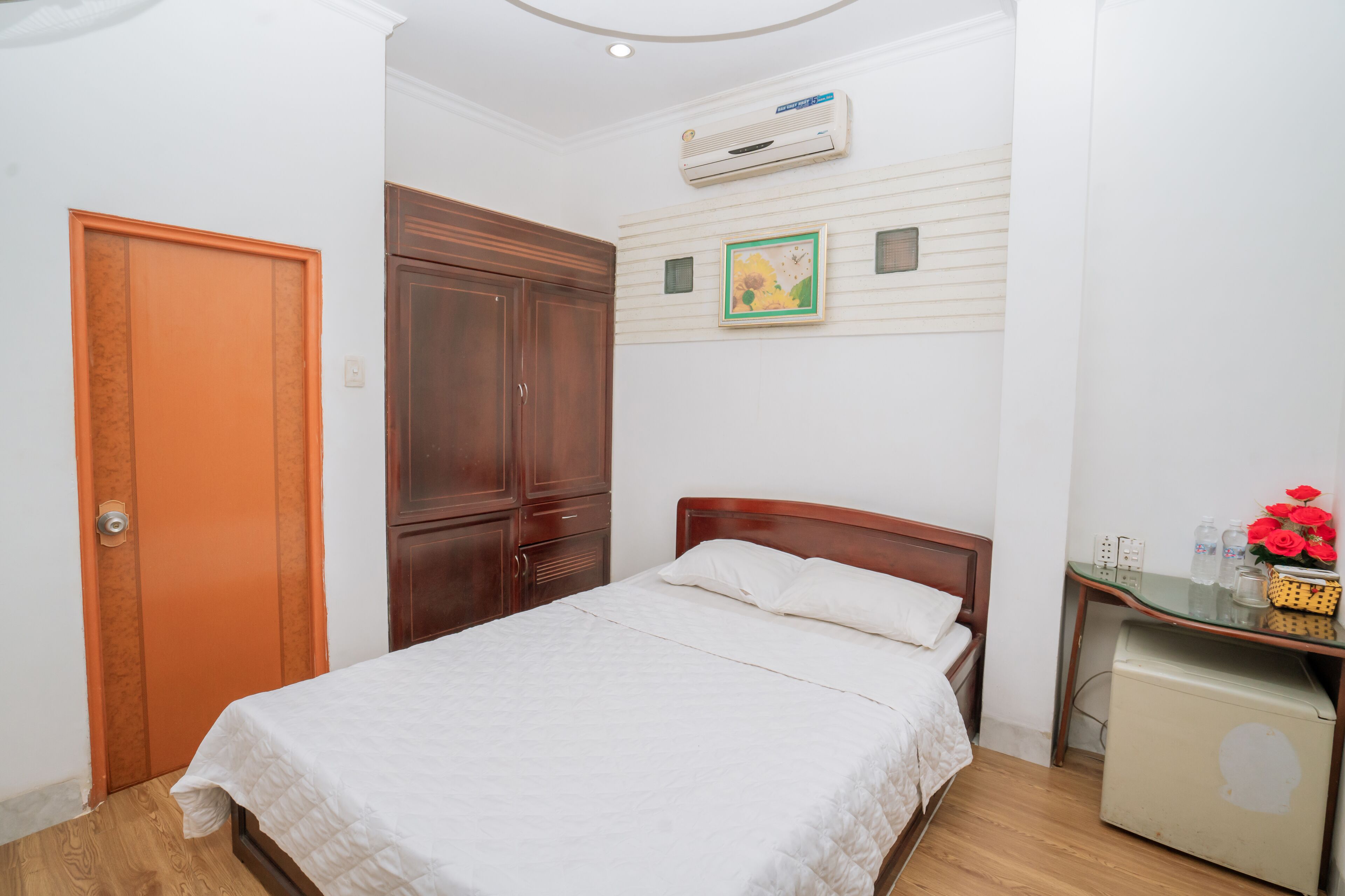 Une chambre à coucher avec un lit, une armoire, un bureau avec un ordinateur et un climatiseur fixé au mur.