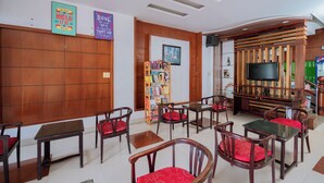 A hotel lobby with wooden paneling, a bookshelf, a television, and several tables and chairs. - Trieu Vu Hotel & Apartment (Buon Ma Thuot)
