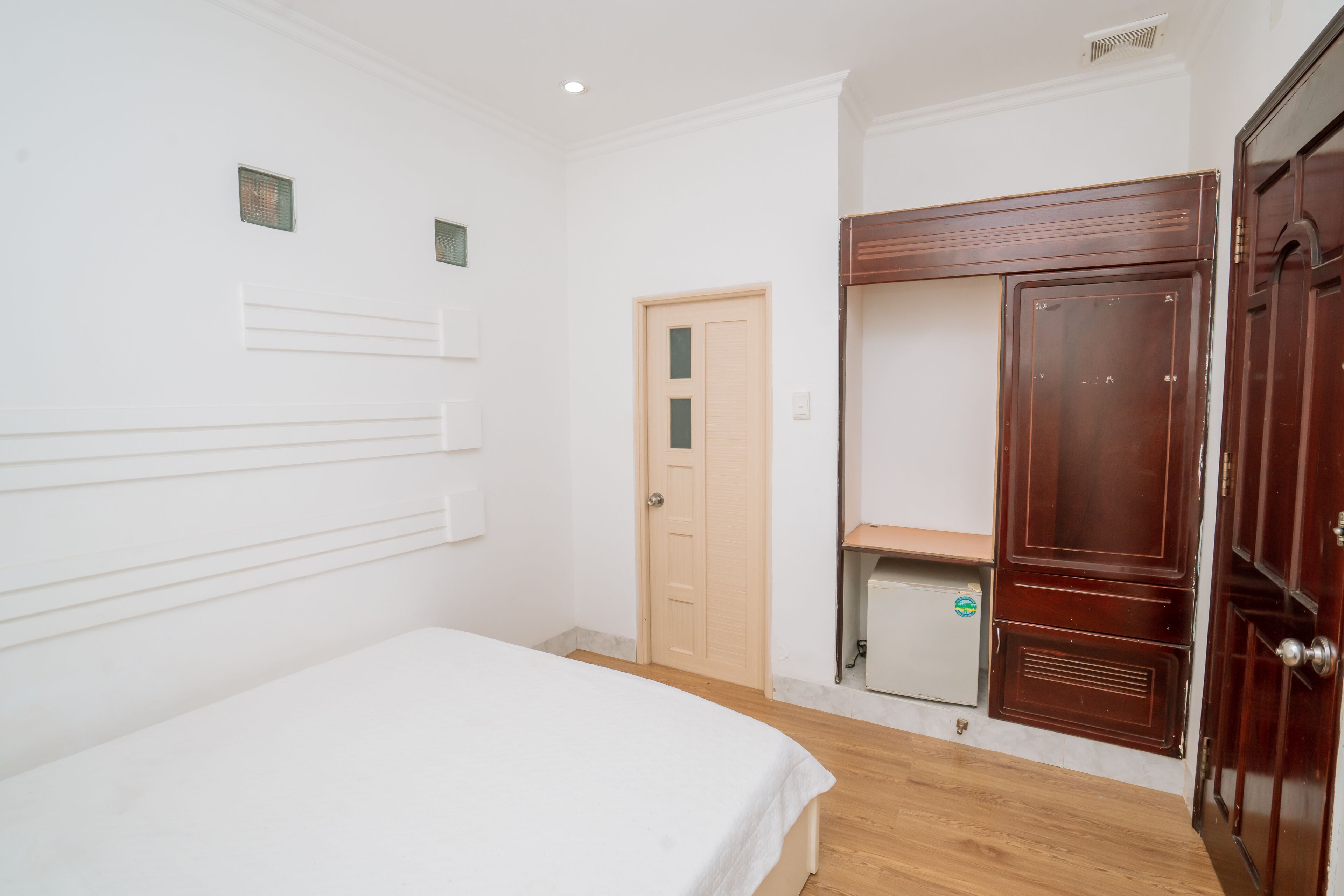 Quarto com cama, guarda-roupa, porta e um pequeno armário.