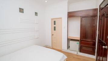 Quarto com cama, guarda-roupa, porta e um pequeno armário.