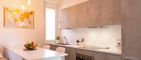 Una cocina moderna con una isla blanca, armarios grises y un mapa mundial en la pared.