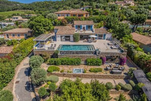 Eine große Villa mit Swimmingpool, Steinterrasse und üppigem Garten.