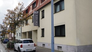 A building with a sign reading "AP HOTEL" and a parked white car.