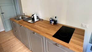 Une cuisine moderne dotée d’un plan de travail en bois, d’un évier en acier inoxydable et d’une plaque de cuisson à induction noire.