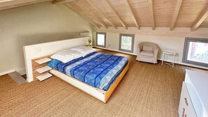 Une chambre avec un plafond en pente, un lit, une chaise et une petite table.