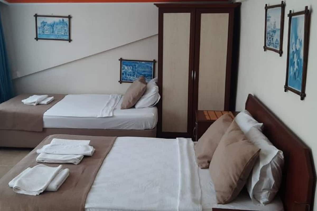 A hotel room with two beds, a wardrobe, and artwork on the walls.